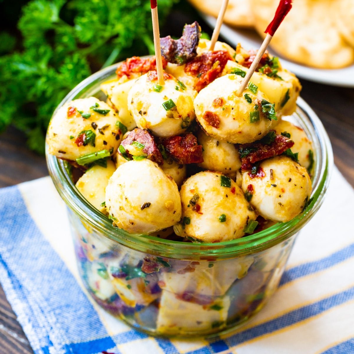 Spicy Marinated Mozzarella Balls in a glass bowl with toothpicks.