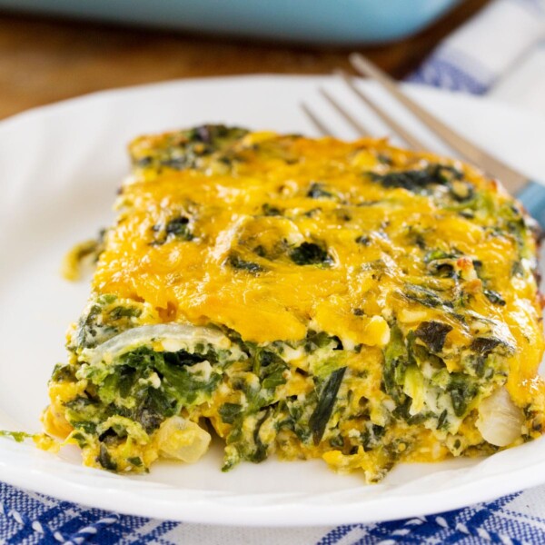 Slice of casserole on a white plate with a fork.