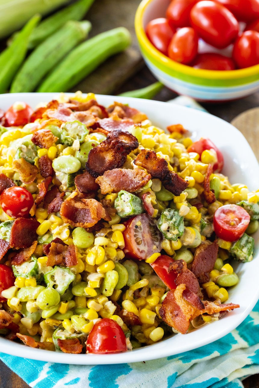 Succotash in a bowl with a bowl of grape tomatoes next to it.