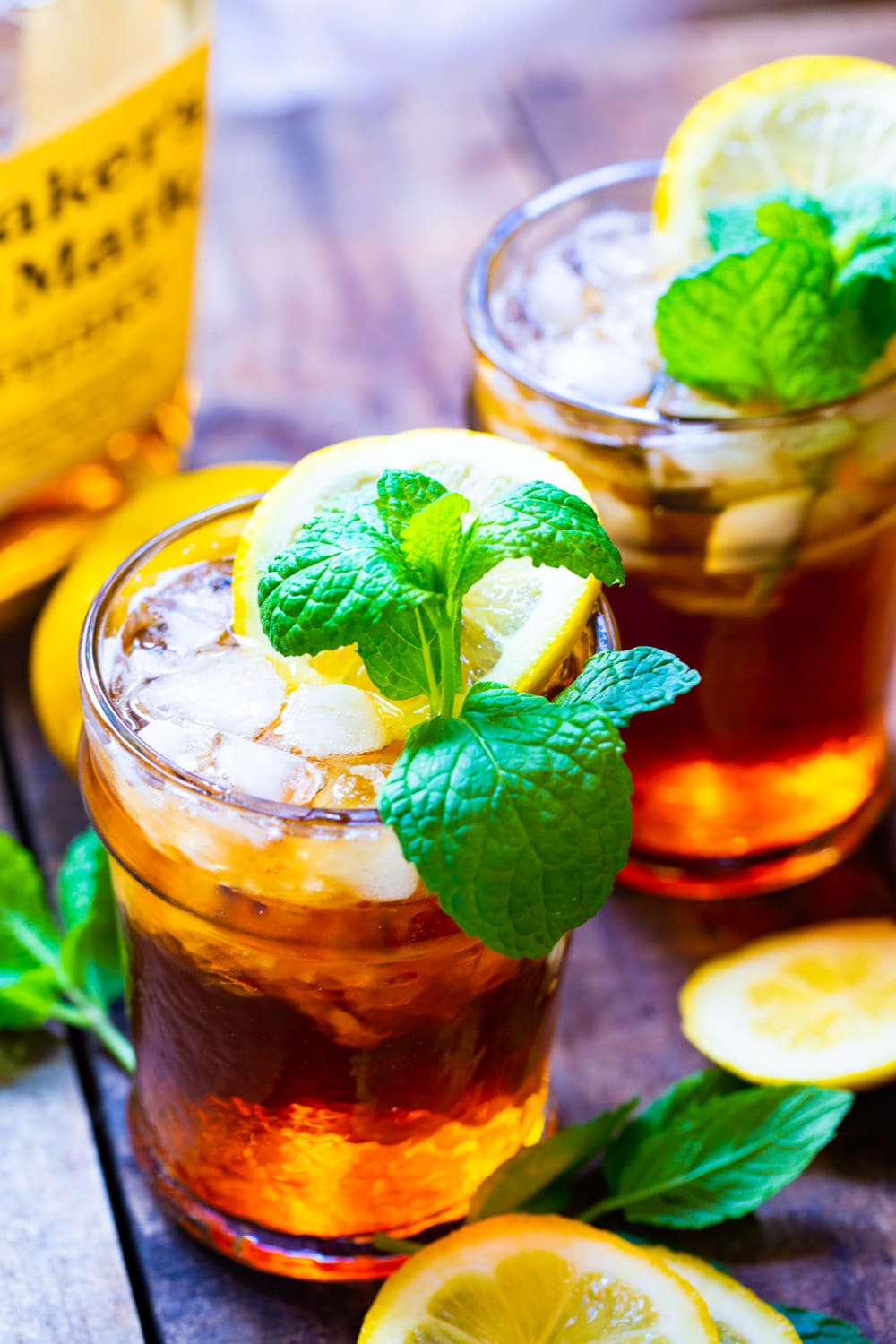 Two Mint Juleps in glasses with lemon slices and mint.