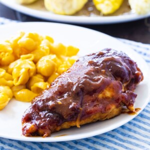 One BBQ Chicken Breast on a plate with mac and cheese.