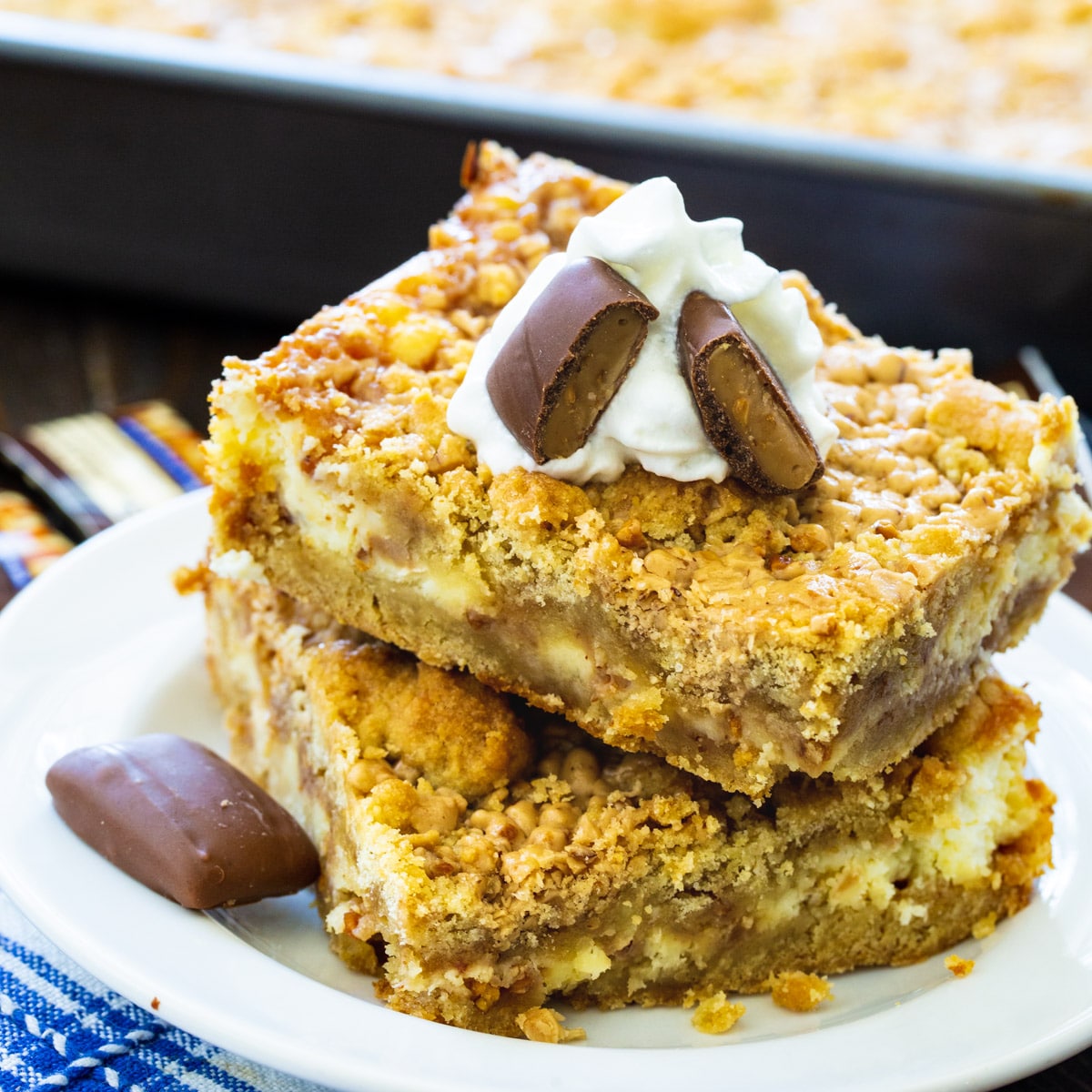 Two Toffee Cheesecake Bars stacked on a plate.