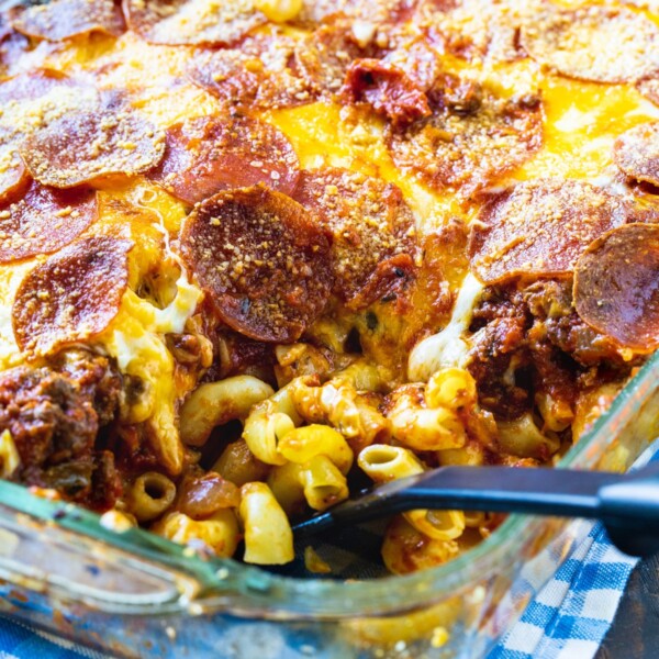 Spoon scooping up Johnny Marzetti Casserole in a 9x13-inch dish.