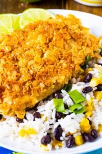 Tortilla Crusted Chicken with beans and rice on a white plate.