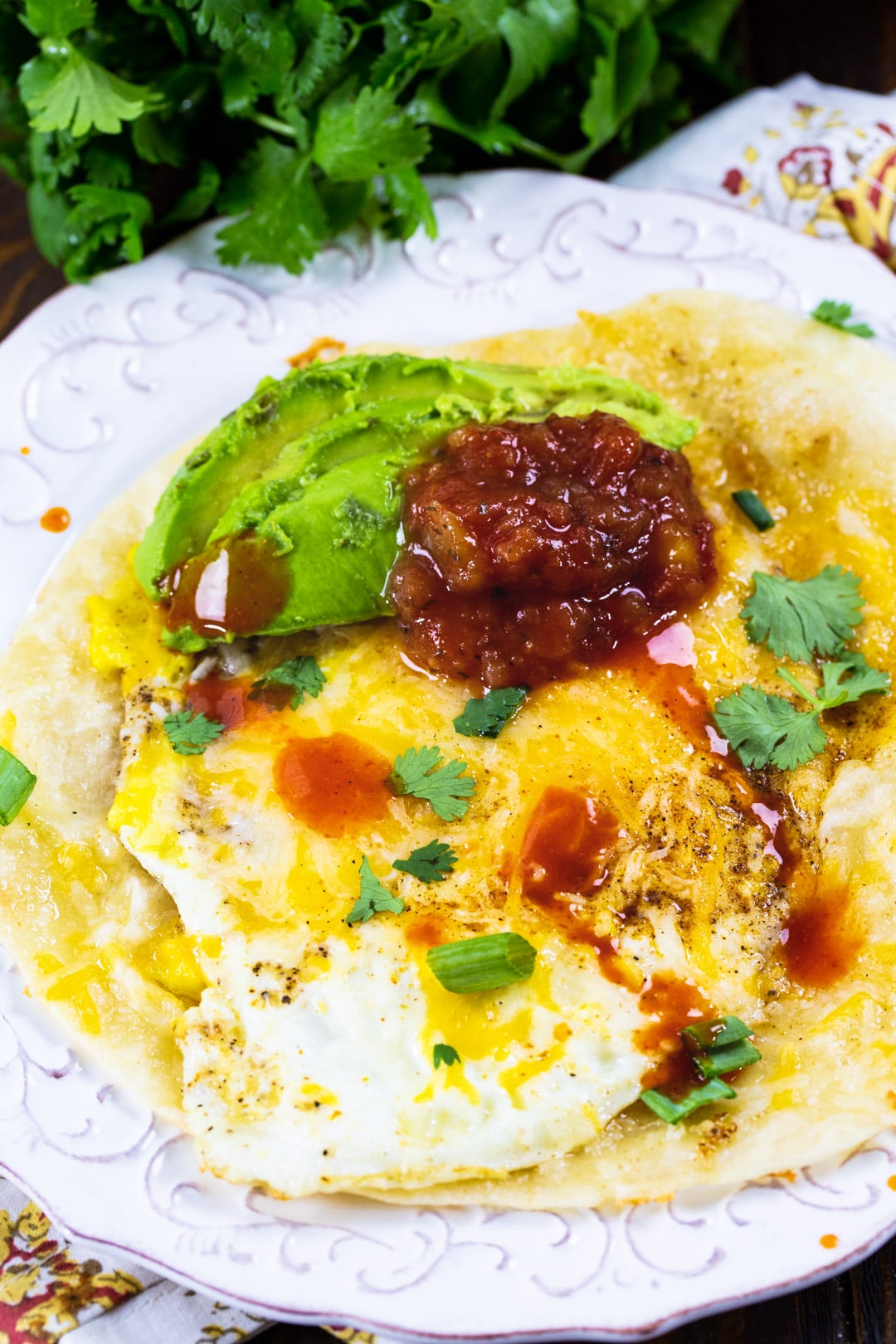 Tortilla Egg topped with salsa and avocado on a plate.
