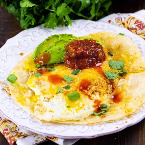 Tortilla Eggs topped with salsa and avocado on a plate.