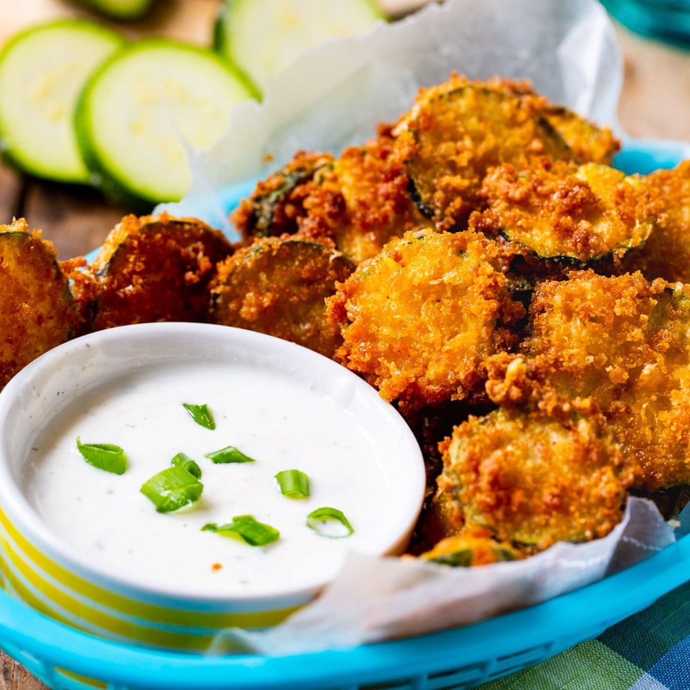 Fried Zucchini Chips with bowl of ranch dressing in a blue basket.