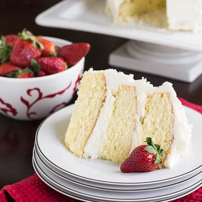 Slice of Almond Cake on a stack of white plates.