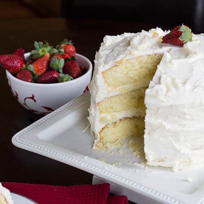 Almond Cake on a cake stand with bowl of strawberries.