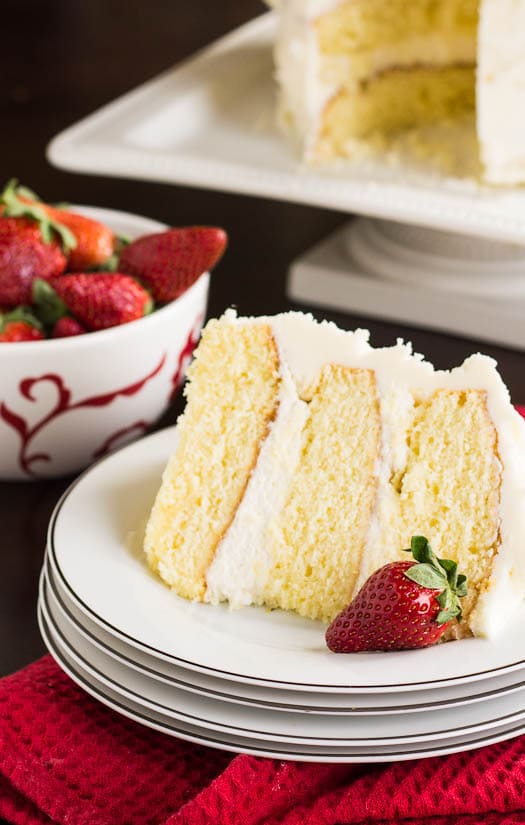 Almond Cake with Amaretto Filling  on a white plate with bowl of strawberries in background.