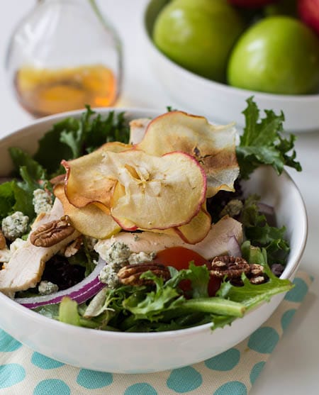 Fuji-Apfel-Hühnersalat mit einer Schale Äpfel im Hintergrund.