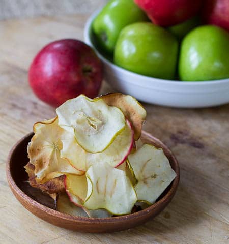 Apple Chips on a small plate with red and green apples in background.