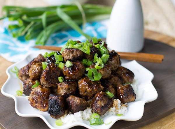 Meatballs piled on a serving plate and topped with green onion.