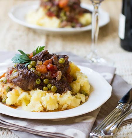 Beef Daube Provencal over mashed potatoes on a white plate.