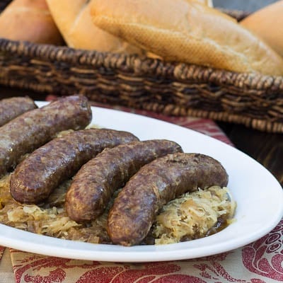Slow Cooker Beer Brats served over sauerkraut on a plate.