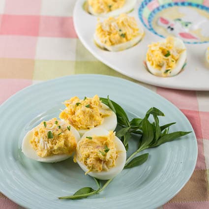 Crab Deviled Eggs on a blue plate with fresh tarragon.