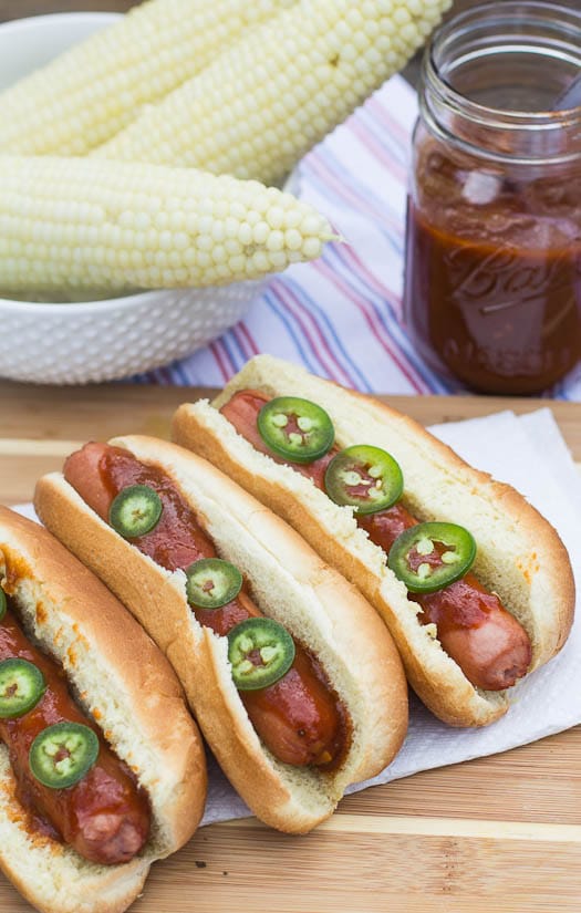 Hot Dogs with Dr. Pepper BBQ Sauce and corn in background.