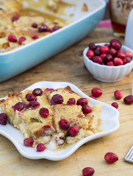 Eggnog French Toast Casserole on small plate with cranberries scattered around.