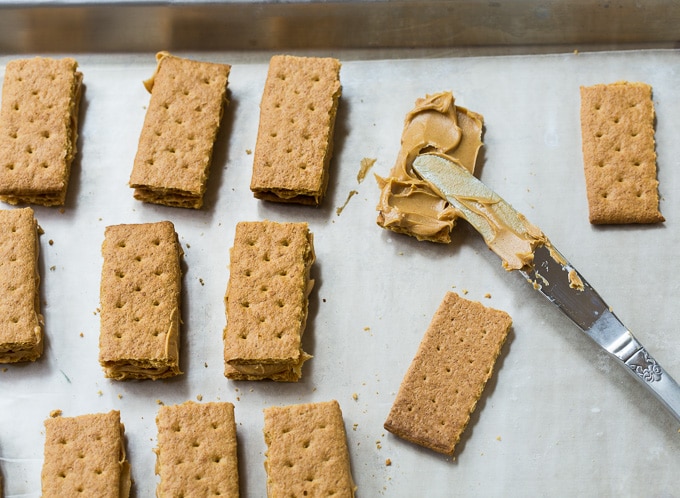 Spread peanut butter on graham crackers.