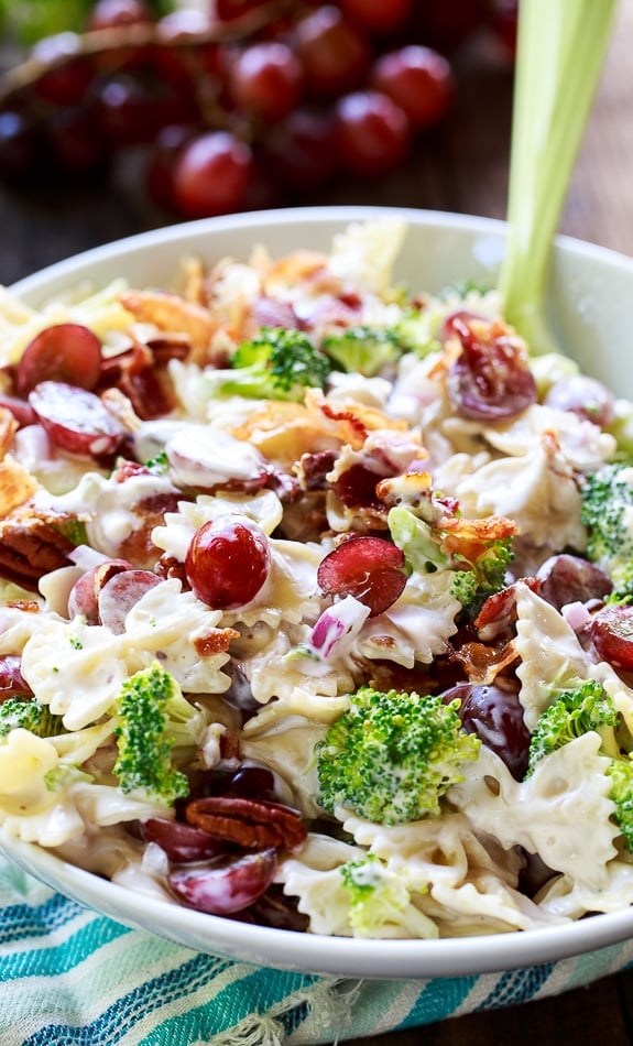 Broccoli Grape Pasta Salad in a white serving bowl with red grapes in background.