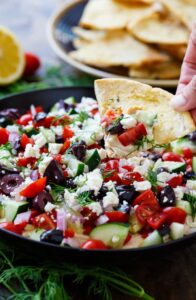 Creamy Greek Dip with cream cheese, hummus, tomatoes, cucumber, olives, feta, and fresh dill.