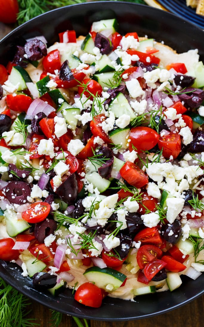 Creamy Greek Dip with cream cheese, hummus, tomatoes, cucumber, olives, feta, and fresh dill.