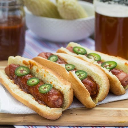 Three hot dogs topped with jalapeno slices.