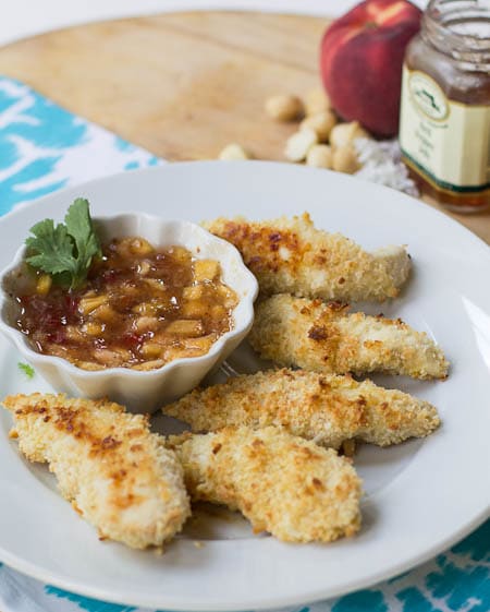 Baked Chicken Tenders on a plate with bowl of Peach Pepper Jelly Sauce.