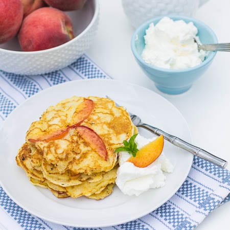 Peach Pancakes on a plate with whipped cream.