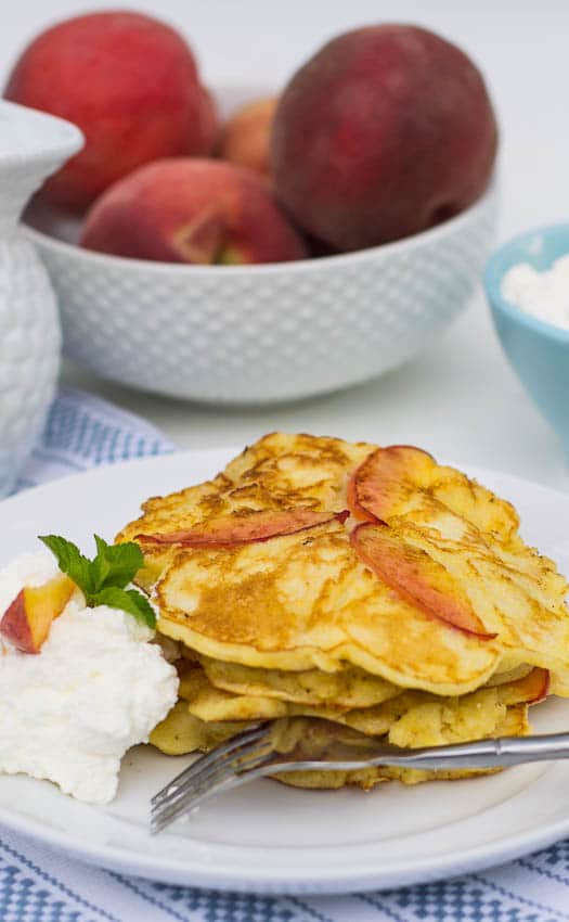 Close-up of stack of Sweet Peach Pancakes with fresh peaches in background.