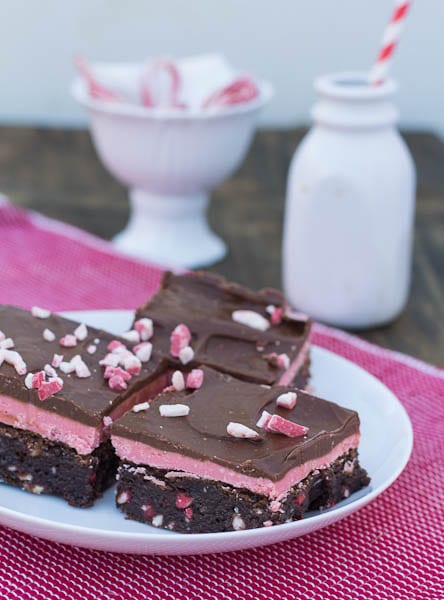 Peppermint Brownies on a plate with bowl of candy canes in background.
