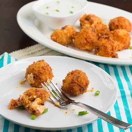 Three Pimento Cheese Balls on a white plate with a fork.