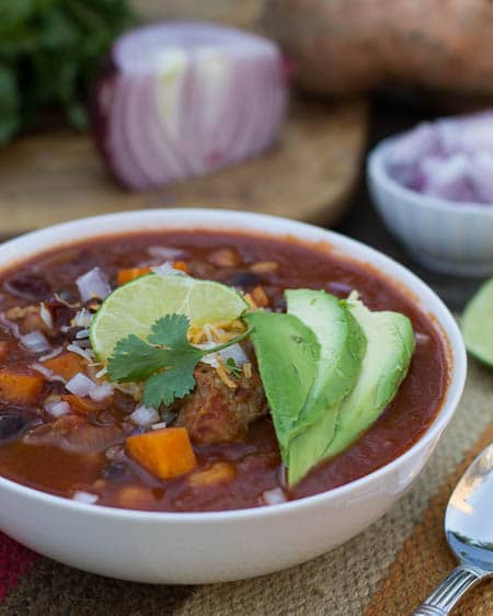 Chipotle Pork and Sweet Potato Posole in a bowl topped with avocado slices.