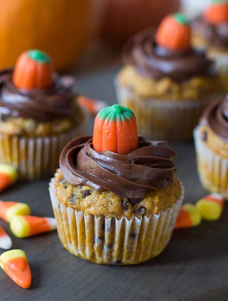 Pumpkin Chocolate Chip Cupcakes topped with chocolate frosting and candy corn pumpkins.