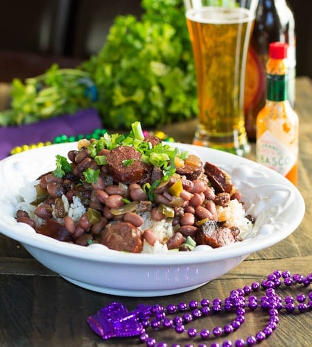 Slow Cooker Red Beans and Rice in bowl with beer in background.