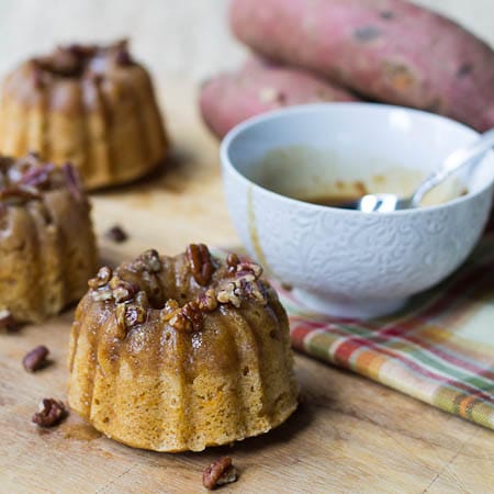 Individual Bundt Cakes flavored with sweet potato with bowl of glaze in background.