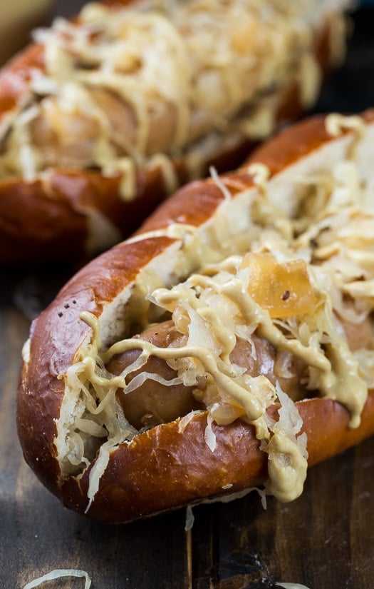 Slow Cooker Beer Brats in hoagie rolls topped with sauerkraut and drizzled with mustard.