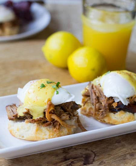 Southern Eggs Benedict on a biscuit with pulled pork. Orange juice and lemons in background.