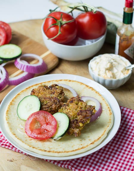 Southern Falafel on pita bread with tomatoes and red onion in background.