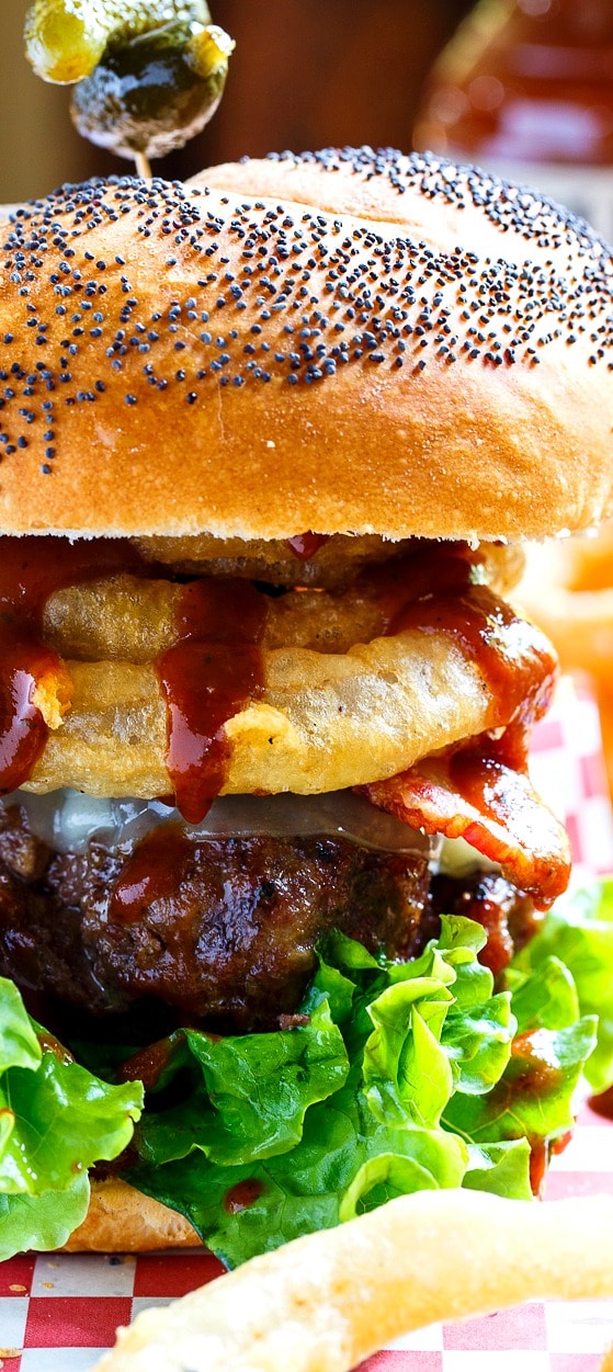 Cowboy Burgers topped with onion rings, bacon, and bbq sauce.
