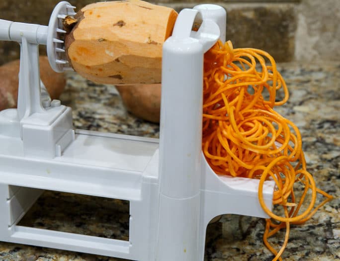 Using a spiralizer to make sweet potato shoestring fries.