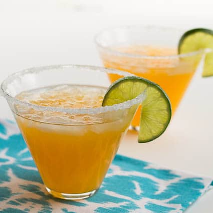 Margaritas in 2 glasses with lime wedges.