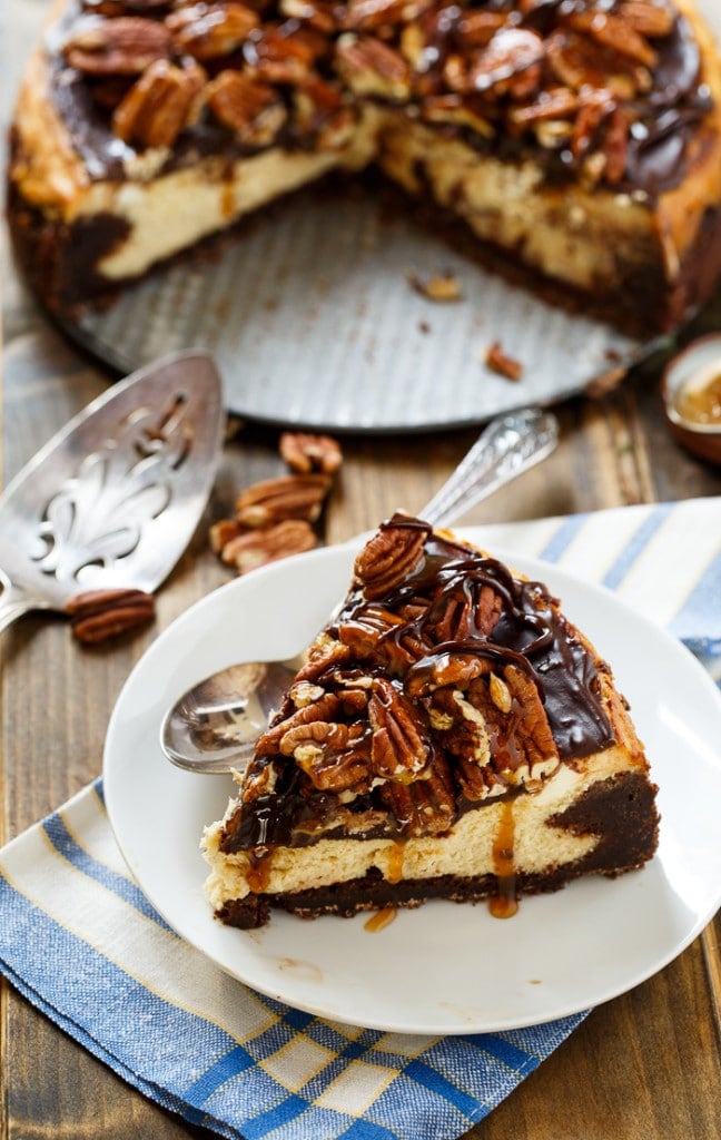 Turtle Brownie Cheesecake with a brownie crust and pecans, caramel sauce, and chocolate sauce on top.