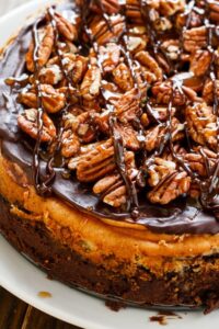 Turtle Brownie Cheesecake with a brownie crust and pecans, caramel sauce, and chocolate sauce.