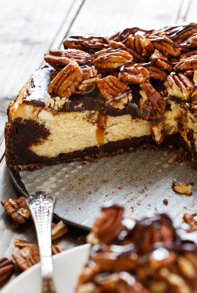 Turtle Brownie Cheesecake with a brownie crust and pecans, caramel sauce, and chocolate sauce on top.