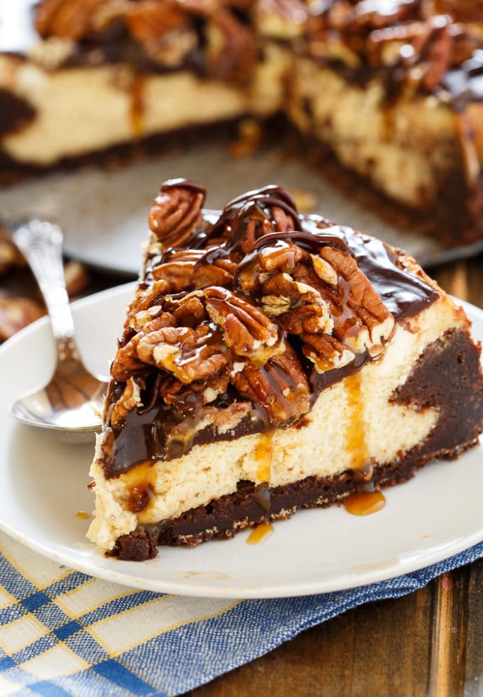 Turtle Brownie Cheesecake with a brownie crust and pecans, caramel sauce, and chocolate sauce on top.